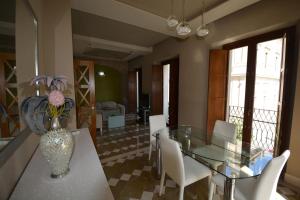 塞维利亚Luxury Apartment with views to Alcazar, Cathedral and Giralda.的一间设有玻璃桌和白色椅子的用餐室