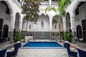 非斯里亚德布拉亚酒店的一座游泳池,位于一座带椅子和树木的建筑中