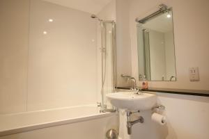 奥古斯都堡Old School Apartments Highland Club的白色的浴室设有水槽和淋浴。