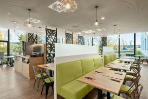 慕尼黑Super 8 by Wyndham Munich City North的餐厅设有木桌和绿色椅子