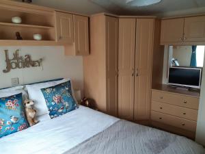 Gilcrux24 The Beeches Caravan Park的一间卧室配有一张床和一台平面电视