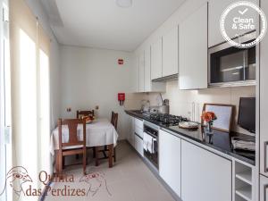 蓬塔德尔加达Quinta das Perdizes的厨房配有白色橱柜、桌子和用餐室。
