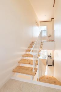 拉廊Hoteru House Ranong 1 - โฮเตรุ เฮ้าส์ ระนอง的房屋内的楼梯,拥有白色的墙壁和木地板