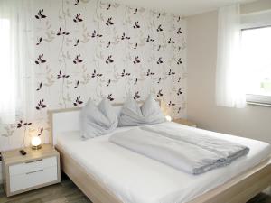 多内斯科尔岑Apartment Fuchs - DON161 by Interhome的卧室配有白色床和花卉壁纸