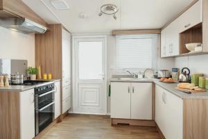 利明顿Heavenly Haven的厨房配有白色橱柜和炉灶烤箱。