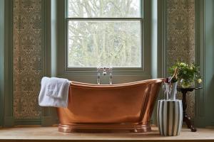 纽伯里The Retreat, Elcot Park的带窗户的浴室内的铜质浴缸