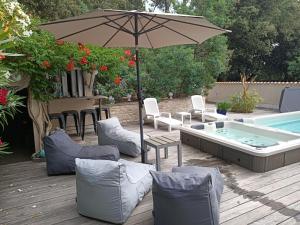 Grand-Village-PlagePomme de Pin et Mimosa的一个带遮阳伞和椅子的庭院和一个游泳池