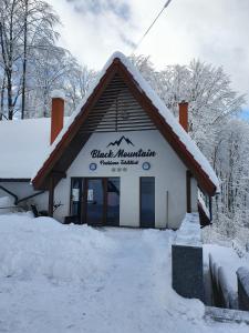 巴亚斯普列Pensiunea Black Mountain的前面的地面上积雪的建筑