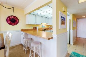 大洋城Ocean Hideaway 511的厨房配有白色橱柜和带凳子的台面