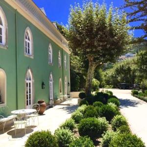 辛特拉辛特拉金塔圣塞巴斯蒂昂之家旅馆的绿色的建筑,有桌子和树