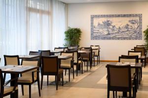 波尔图TRYP by Wyndham Porto Centro Hotel的用餐室配有桌椅,墙上挂有绘画作品