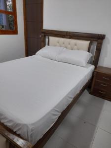 埃尔扎伊诺Hostal Y Balneario La Danta的一张铺有白色床单的床和木制床头板