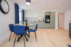 沃特福德Watford Cassio Deluxe - Modernview Serviced Accommodation的厨房以及带桌子和蓝色椅子的用餐室。