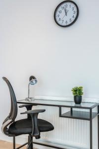沃特福德Watford Cassio Deluxe - Modernview Serviced Accommodation的玻璃桌,椅子和墙上的时钟