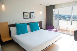 库库塔库库塔卡萨布兰卡酒店的卧室配有带蓝色枕头的大型白色床