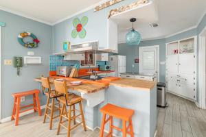 泰比岛My Tybee Queen的厨房设有蓝色的墙壁和橙色的酒吧凳子