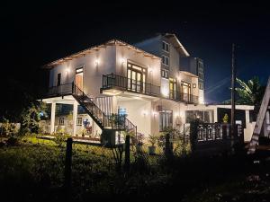 阿努拉德普勒Theon Resort的一间白色的大房子,晚上有灯