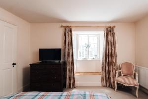 Shipton MoyneCat and Custard Pot Inn的一间卧室设有一张床、一台电视和一个窗口。
