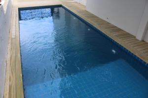 弗洛里亚诺波利斯Innbox - Canasvieiras 2的一个带木制甲板的大型蓝色游泳池