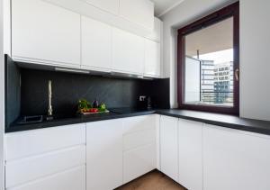 克拉科夫P&P Apartments的厨房配有白色橱柜和窗户。