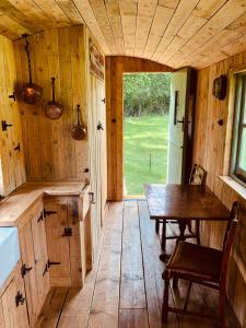 查尔伍德The Big Green Shepherds Hut的厨房铺有木地板,配有木桌。