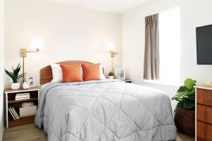 格林伍德InTown Suites Extended Stay Indianapolis IN - Greenwood的白色卧室配有带橙色枕头的床