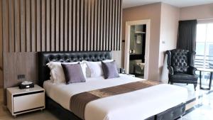 芭堤雅市中心KTK Pattaya Hotel & Residence的一间卧室配有一张大床和一张黑椅
