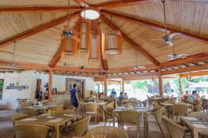 麦克坦Bluewater Maribago Beach Resort的餐厅设有木制天花板和桌椅