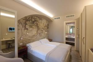 勒威诺Relais Villa Porta的卧室配有白色的床和石墙