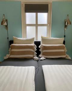 坎珀兰Het Koetshuis的客房设有两张带枕头的床和窗户。