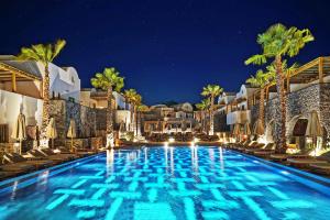 卡马利Radisson Blu Zaffron Resort, Santorini的夜间酒店游泳池,带椅子和棕榈树