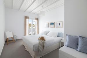 米克诺斯城Amperian Mykonos Suites & Villas的一间白色的卧室,配有一张带帽子的床