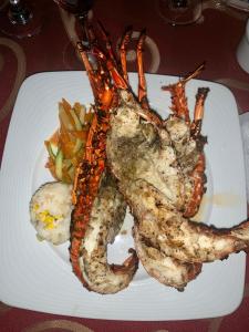 塔果鲁达Paradise Huatulco Condo TANGOLUNDA BEACH的桌上一盘带龙虾和蔬菜的食物