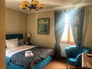 希维博津兰尼夫卡的一间卧室配有一张床、一把蓝椅和一个窗户。
