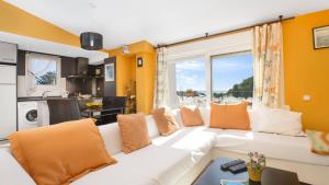 卡莱利亚德帕拉弗鲁赫尔Atic Mar - Calella de Palafrugell的客厅配有带橙色枕头的白色沙发