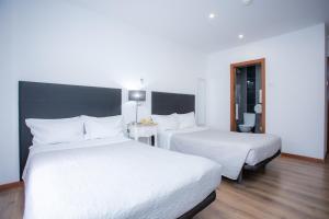 科英布拉多莫斯酒店的酒店客房,配有两张带白色床单的床