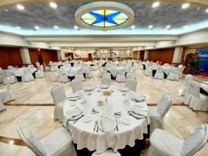 雷阿尔城圣锡西利亚酒店的一个带白色桌椅的大型宴会厅