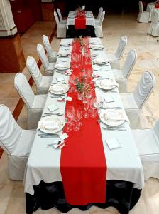 雷阿尔城圣锡西利亚酒店的一张长桌,配有白色椅子和红色及白色的桌布