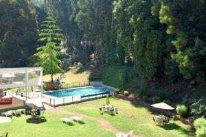 维纳德马Hotel Bosque de Reñaca的庭院内的游泳池,配有桌椅