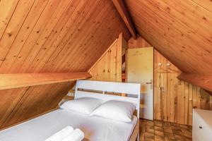 卡布尔Calm chalet close to Cabourg center - Welkeys的木墙和天花板的客房内的一张床位