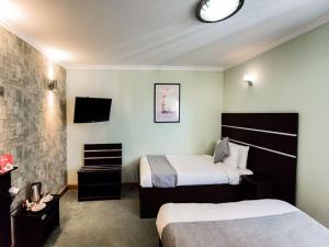 伦敦Epsilon Hotel的一间酒店客房,设有两张床和电视
