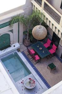 马拉喀什Riad Dar Habiba by Garden Wonders的享有游泳池的顶部景致,配有粉红色的椅子和一张桌子