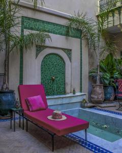 马拉喀什Riad Dar Habiba by Garden Wonders的喷泉前的粉红色椅子