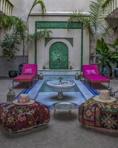 马拉喀什Riad Dar Habiba by Garden Wonders的庭院设有2把粉红色的椅子和喷泉