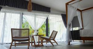 KumbatangEagle Bay Retreat Borneo Beach Villas Beach Front的一间卧室配有两把椅子和一张床,设有窗户。