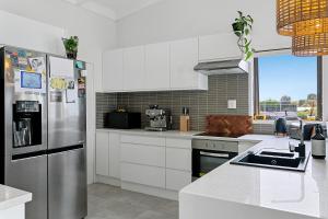 陶波Acacia Bay的厨房配有白色橱柜和不锈钢冰箱