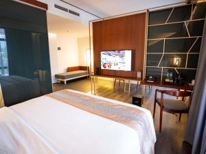 玛琅Rayz UMM Hotel Malang的一间卧室配有一张床、一张书桌和一台电视。