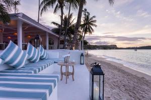 苏梅岛Tembo Beach Club & Resort的海滩酒吧配有蓝色和白色的枕头和桌子
