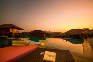 瑟格莱什布尔Machaan Plantation Resort, Sakleshpur的坐在游泳池畔的桌子上喝一杯葡萄酒