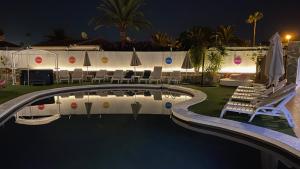 马斯帕洛马斯彩虹高尔夫别墅度假酒店，仅限男同性恋者的夜间游泳池,配有椅子和遮阳伞